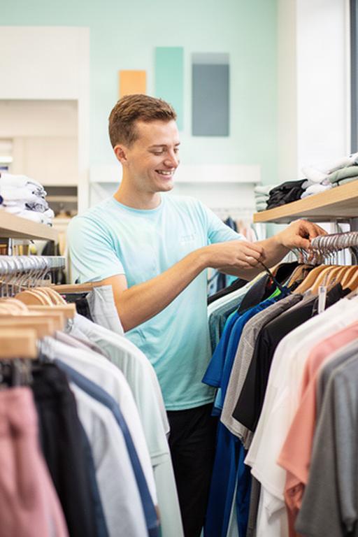 Medewerker in sportwinkel in Epe die kleding aan een rek controleert